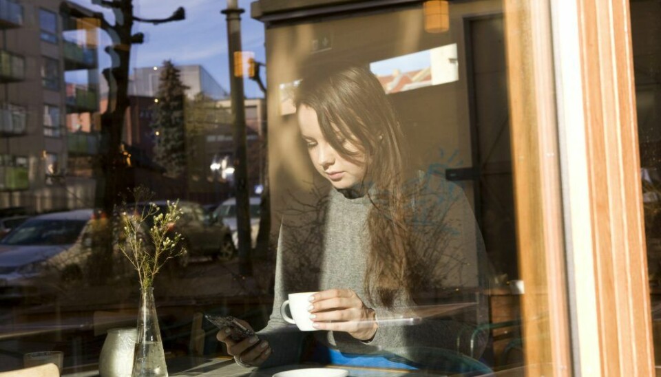 Ung kvinne på cafe på Grünerløkka. Drikker kaffe. Sjekker mobilen. Mobiltelefon. Smarttelefon. NB! MODELLKLARERT Foto: Thomas Brun / NTB