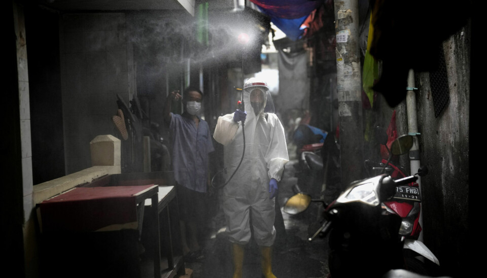 An Indonesian Red Cross (PMI) worker sprays disinfectant in a narrow alley at a low income neighborhood amid fears of another wave of the coronavirus outbreak in Jakarta, Indonesia, Saturday, Feb. 5, 2022. Indonesia is bracing for a third wave of COVID-19 infections as the highly transmissible omicron variant drives a surge in new cases, health authorities and experts said. (AP Photo/Dita Alangkara)